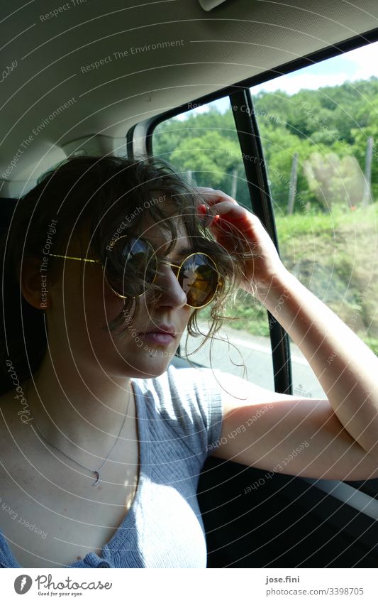 Jugendliche mit Sonnenbrille, sitzt im Auto. Porträt Locken Lifestyle Junge Frau feminin hübsch cool stylisch jung Autofahren Schönes Wetter Natur lässig Urlaub