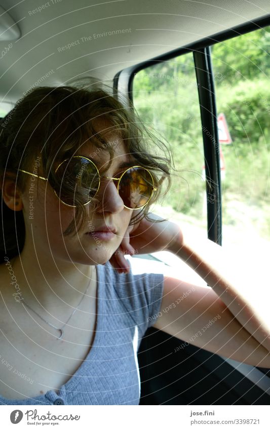 Jugendliche mit Sonnenbrille, sitzt im Auto. Porträt Locken Lifestyle Junge Frau feminin hübsch cool stylisch jung Autofahren Fahrtwind Schönes Wetter Natur