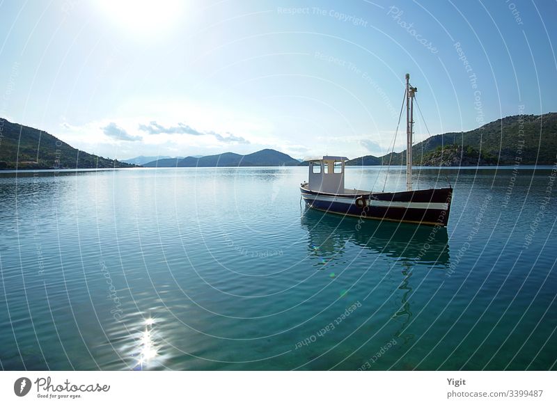 Dunkelblaues Fischerboot in einer Bucht verankert ägäisch Boot Windstille Wolken dunkelblau Insel Hügel mediterraner Meer alt friedlich Reflexion & Spiegelung