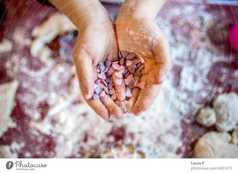 Kleine Kinderhände, die herzförmige Süßigkeiten halten Hände Herzen Liebe Farbfoto rosa purpur Essen zubereiten backen Mehl Finger Beteiligung wüst Nahaufnahme