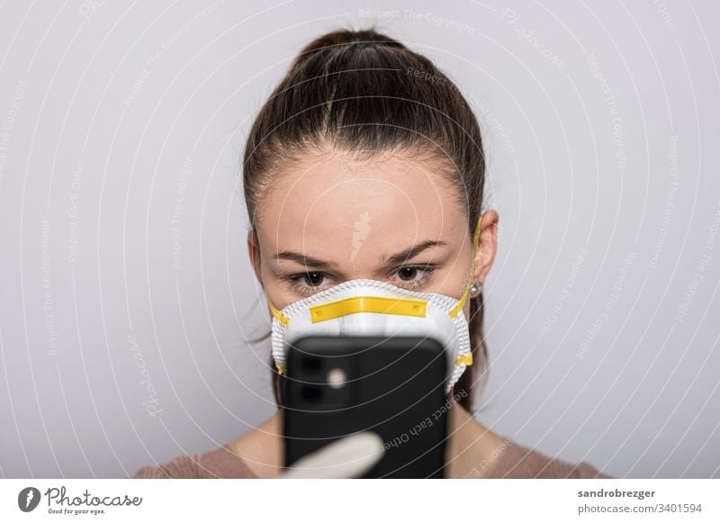 Frau mit Mundschutz und Einmalhandschuhen tippt auf dem Handy Coronavirus COVID-19 Virus Krankheit Pandemie Epidemie Maske Schützen Handschutz Steril Medizin