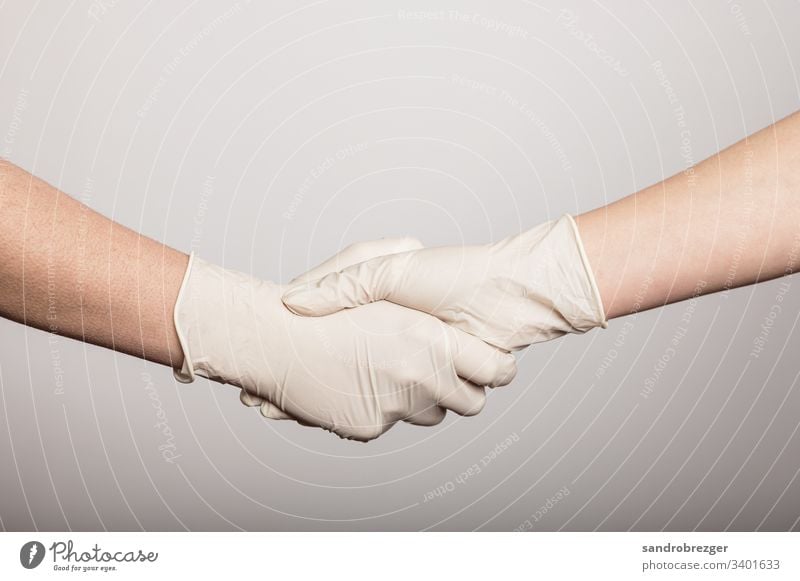 Handschlag in Zeiten des Corona Virus Coronavirus COVID-19 Krankheit Pandemie Epidemie Mundschutz Maske Schützen Einmalhandschuhe Handschutz Steril Medizin