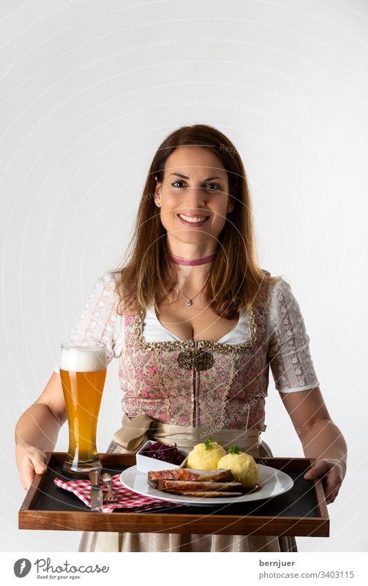 Frau in einem bayerischen Dirndl mit Tablett Abendessen halten weiß isoliert Oktoberfest Schweinebraten Servieren tragen Alkohol Kellnerin tracht Weizenbier