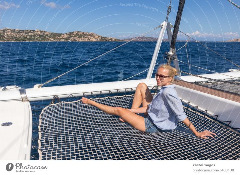 Frau entspannt sich auf einer sommerlichen Segelkreuzfahrt, sitzt auf einem Luxuskatamaran und segelt im Maddalena-Archipel, Sardinien, Italien. Boot Katamaran