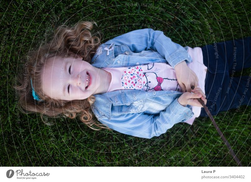 Hübsches blondes kleines Mädchen, das auf dem Gras liegt und lacht - von oben gesehen schön Porträt Kind wenig Verlegung Rücken grün Sommer Lachen Spielen