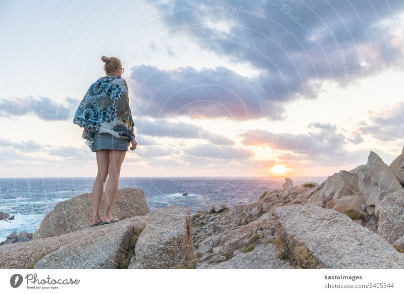Eine junge Reisende beobachtet als Solistin einen wunderschönen Sonnenuntergang auf den spektakulären Felsen von Capo Testa, Sardinien, Italien. reisen
