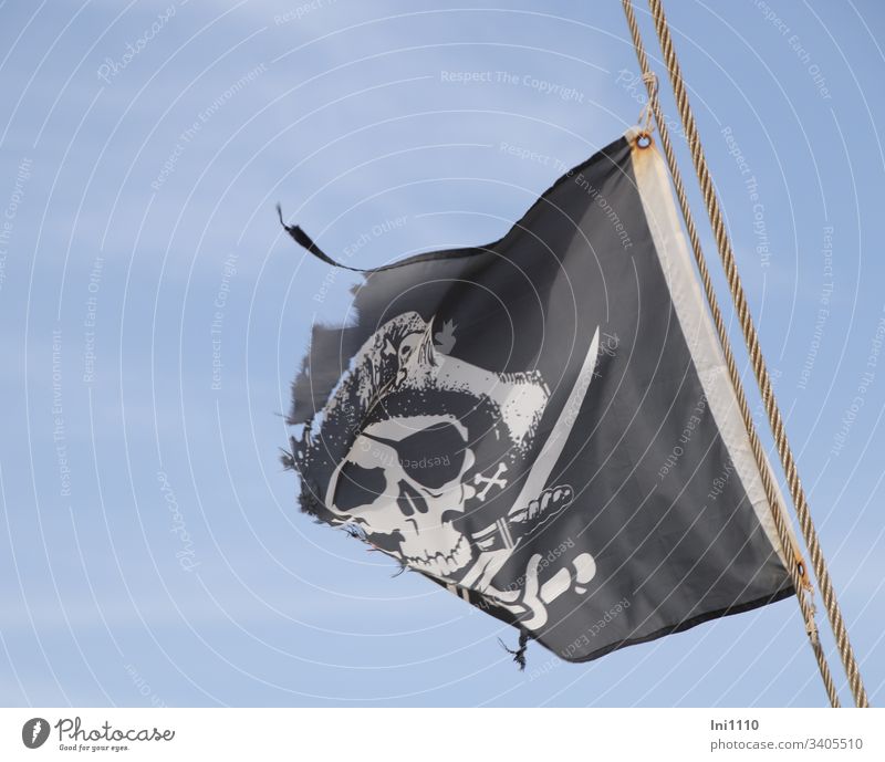 zerfledderte schwarz weiße Piratenflagge am Seil vor blauem Himmel Flagge Flaggenseil Piratenhut schwarzer Hintergrund Totenkopf Augenklappe Säbel Schwert