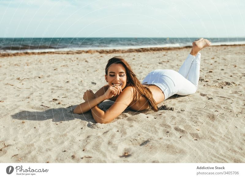 Fröhliche junge Oben-ohne-Frau am Strand oben ohne sensibel liegen sandig Sonnenlicht Sommer feminin Versuchung verführerisch natürlich Model charmant