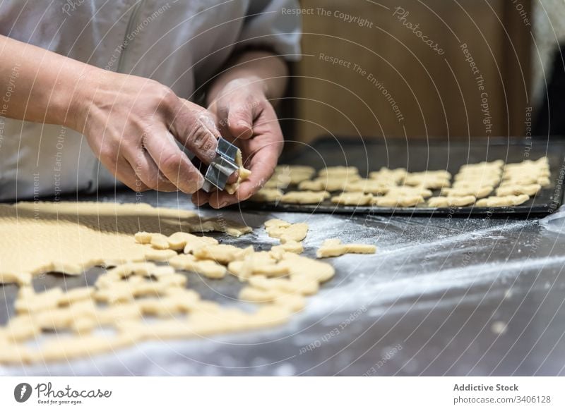 Getreidebäcker, der Kekse auf dem Tisch backt Bäcker geschnitten Bäckerei Teigwaren Mehl Koch Küchenchef Arbeit Kutter Werkzeug Lebensmittel Gebäck Bestandteil