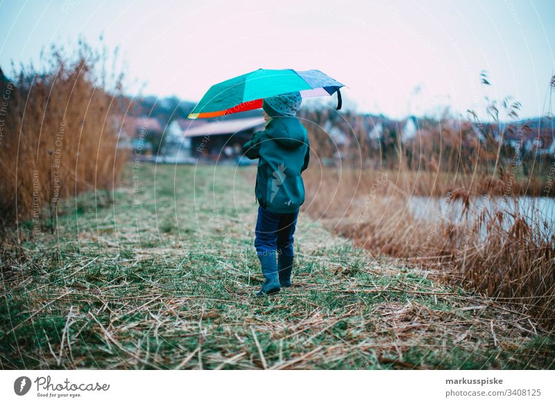 Junge mit bunten Regenschirm Wetterschutz Regenwetter Entdecker entdecken Gummistiefel