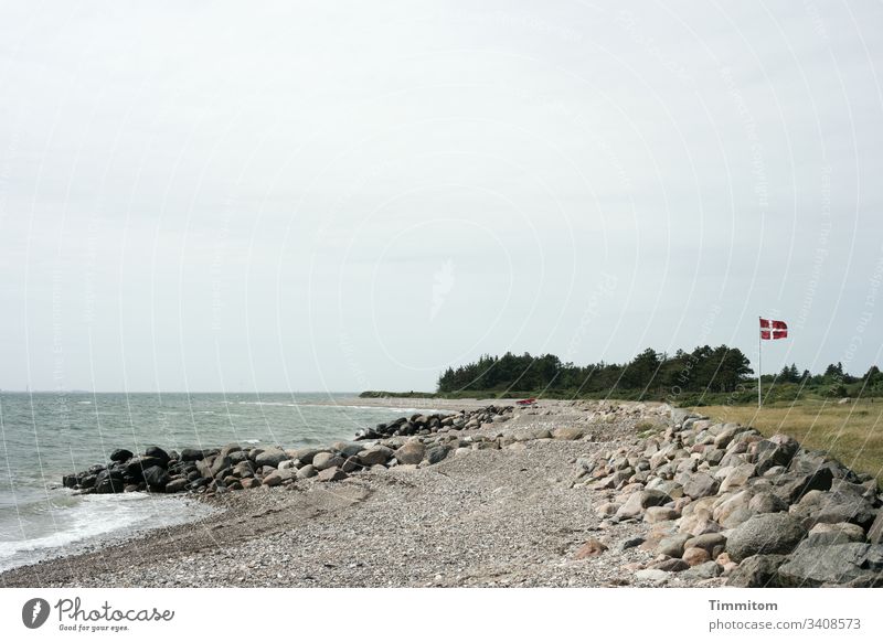 Dänische Fahne im Wind Dänemark Nordsee Wasser Strand Steine Landzunge Gras Bäume Himmel Wolken Farbfoto Menschenleer Ferien & Urlaub & Reisen Natur