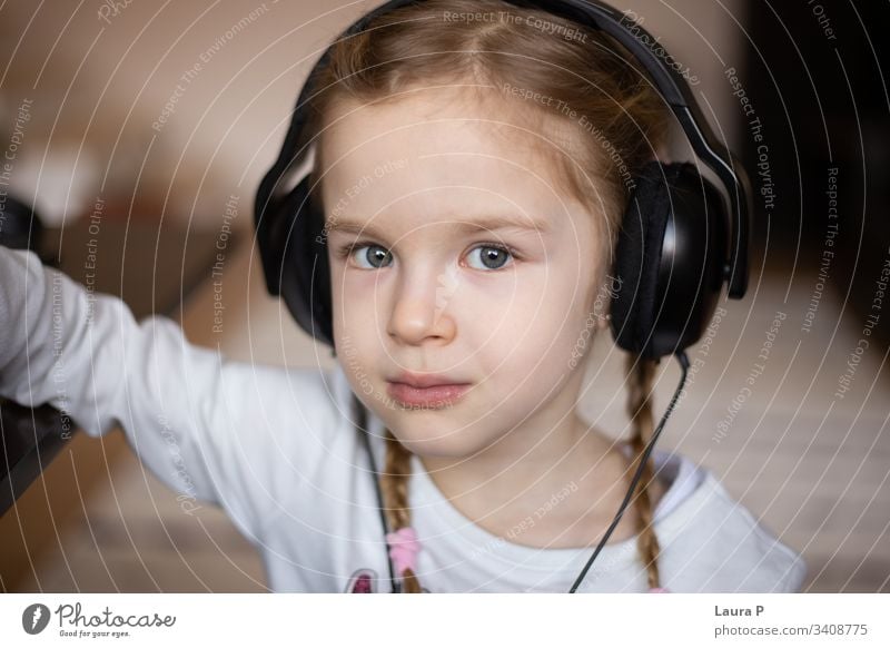 Nahaufnahme eines schönen blonden kleinen Mädchens, das über Kopfhörer Musik hört abschließen wenig Kind zuhören grün Auge Musik hören Erholung genießen Freude