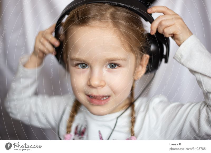 Nahaufnahme eines schönen blonden kleinen Mädchens, das über Kopfhörer Musik hört Lächeln Glück jung Schönheit Kind wenig Tochter Spaß niedlich genießen