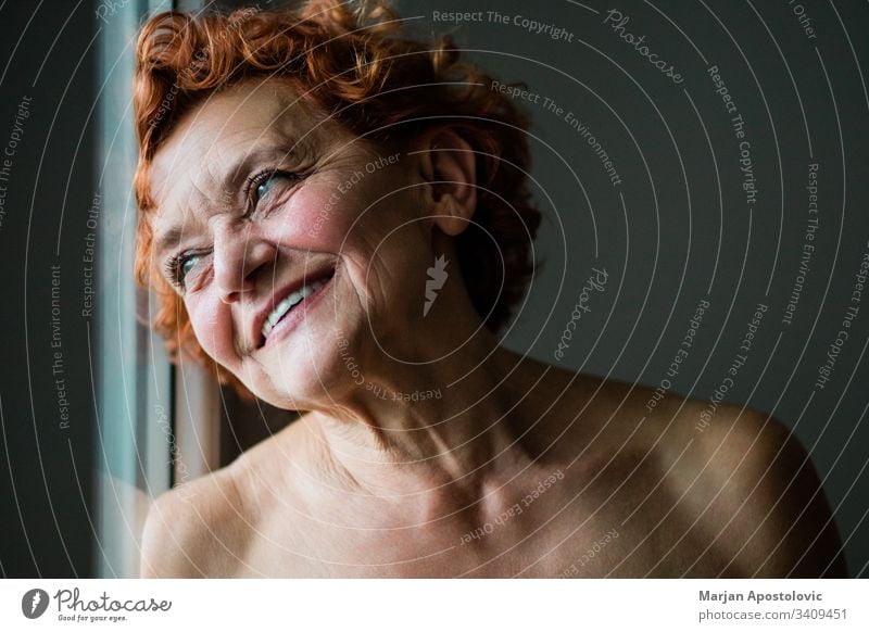 Glückliche reife Frau lächelt am Fenster 60s Erwachsener Lebensalter gealtert Alterung attraktiv schön Schönheit Pflege sorgenfrei Kaukasier charmant heiter