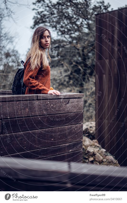 Frau auf einer Holzstruktur, die in die Kamera schaut Model schön posierend Herbst Schönheit Touristik Straße Stiefel allein Lächeln sorgenfrei Glamour urban