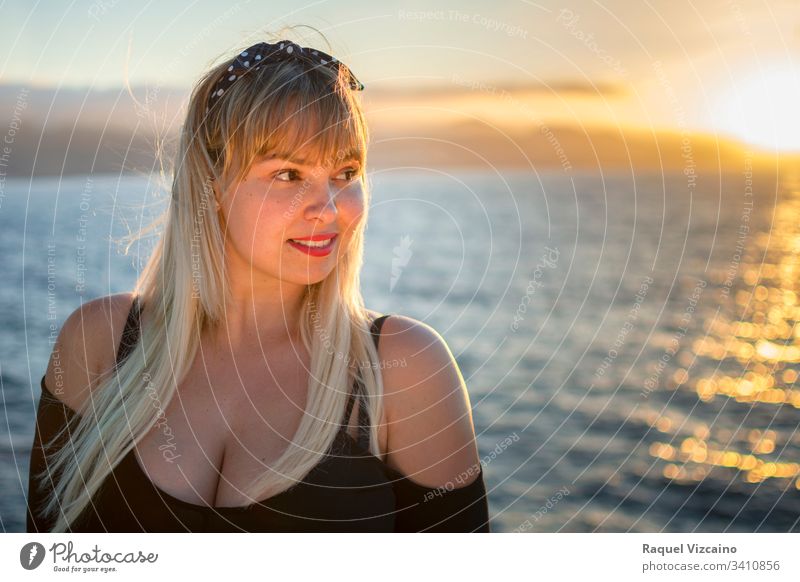 Porträt einer blonden Frau mit dem Meer im Hintergrund und vom abendlichen Sonnenlicht beleuchtet. Strand schön MEER jung Schönheit Sommer Sonnenuntergang Glück