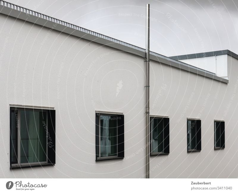 Weiße Fassade mit schwarzen Fenstern vor grauem Himmel Haus weiß Fenterrahmen Perspektive Rohr Stein Gebäude menschenleer Stadt trist selbstbewusst bescheiden