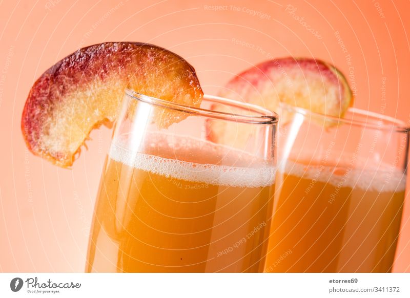 Bellini Champagner-Cocktail in Kristallglas auf orangem Hintergrund. Nahaufnahme Alkohol Aprikose bellini Getränk Weinbrand Schaumblase klassisch lecker trinken