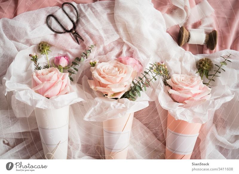 Blumensträuße in Papierkegeln Zapfen Kegel weiß Kornetts Roséwein Rosen Pastell Hintergrund Blumenstrauß vereinzelt Valentinsgruß Tag rosa grün Frühling geblümt