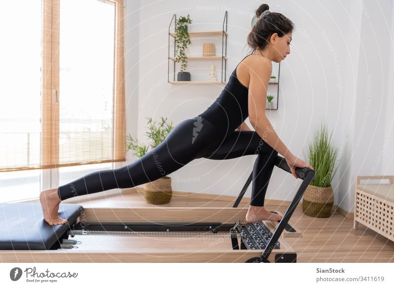 Junge Frau trainiert auf Pilates-Reformer-Bett jung Mädchen Fitness Übung Fitnessstudio Gerät Training Gesundheit Körper Lifestyle Flexibilität passen aktiv