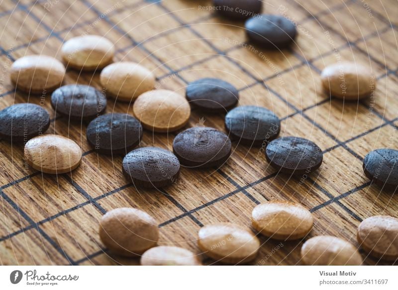 Hölzerne gemischte Chips über einem Brett des traditionellen chinesischen Spiels namens GO abstrakt antik Holzplatte Chinesisch Nahaufnahme Farbe Kultur