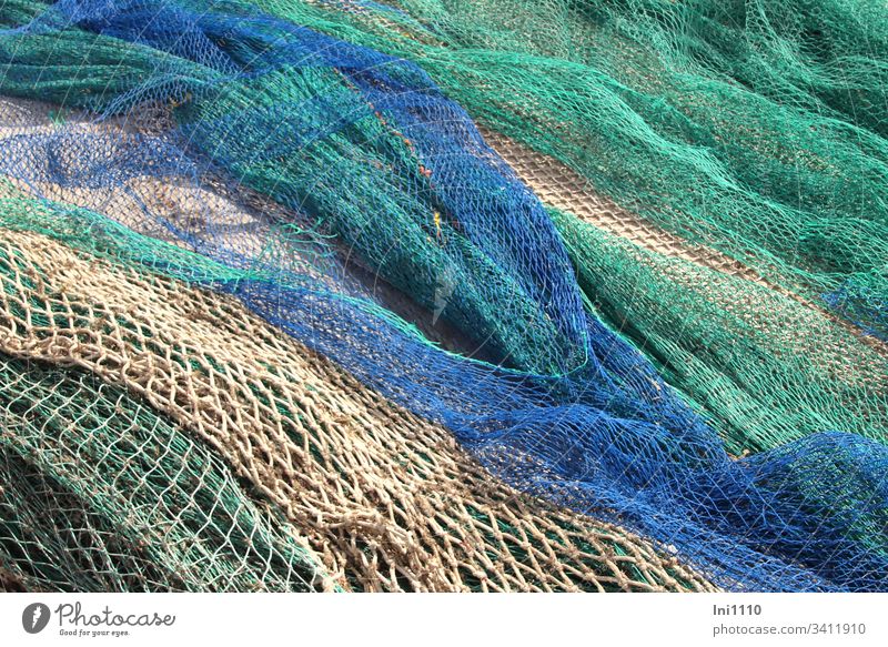 farbige Fischernetze liegen am Kai zur Reparatur Mallorca blau grün beige Fischfang Hafen Handwerk Seefahrt Beruf Maschen Meeresfarben menschenleer Natur