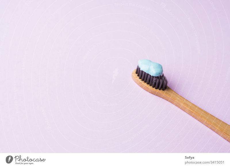 Bambus-Zahnbürste auf rosa Pastell-Hintergrund Hygiene dental Zahncreme blau Personal Fliederbusch Konzept Frühling Zähne trendy mündlich modern sehr wenige