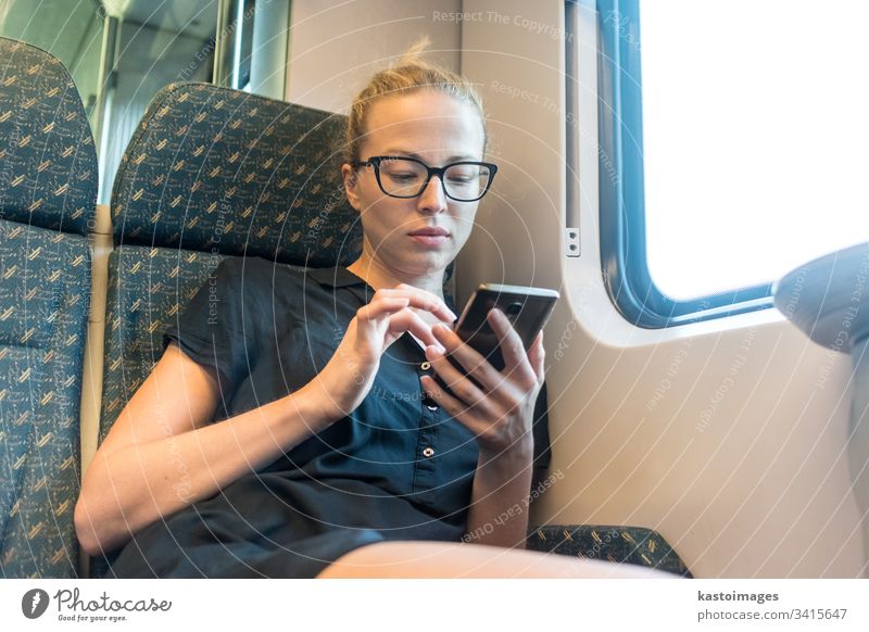 Weibliche kaukasische Reisende, die während einer Zugreise Mobiltelefonanwendungen nutzen. Telefon reisen Frau Verkehr jung Passagier klug Dame Reisender Glück