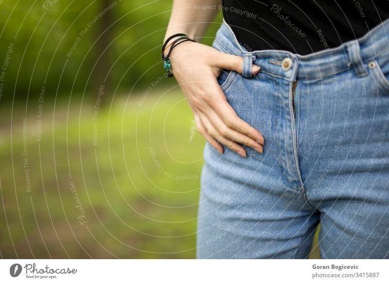 Frau in Denim passen schlank posierend im Freien Park Finger Hände Hose Jeanshose Mädchen Jeansstoff Körper jung hippe Reißverschluss Konfektionsgröße