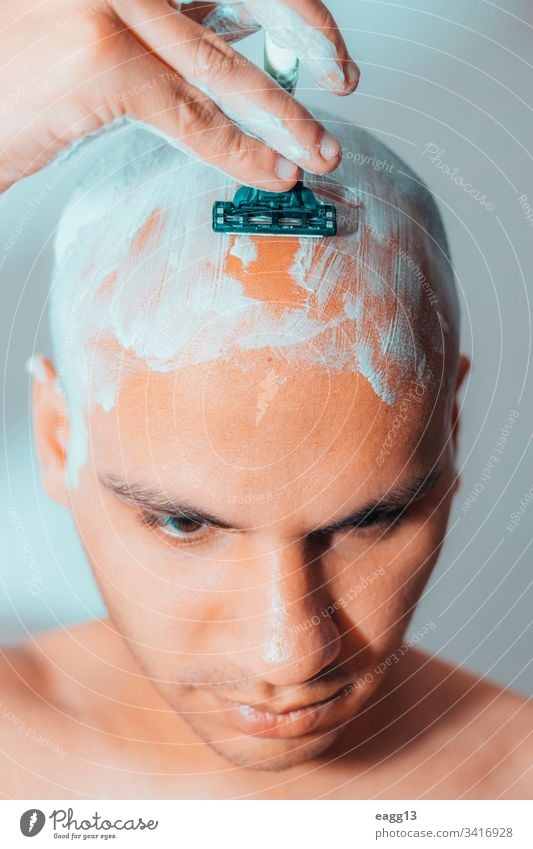 Mann rasiert seinen Kopf mit weißem Schaumstoff Vorschein kahl kahl werdend Bad Klinge Pflege Konzentration abgeschnitten Enthaarung Tatkraft Ausdrücken Auge