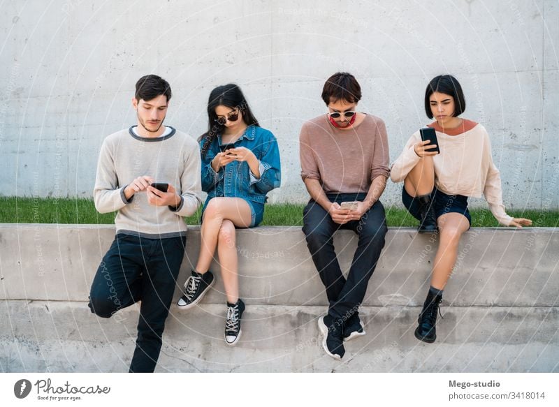 Gruppe von Freunden, die ihr Telefon benutzen. Handy Freundschaft Menschen jung vier Personen Drahtlos Gerät Zusammengehörigkeitsgefühl modern Touchscreen