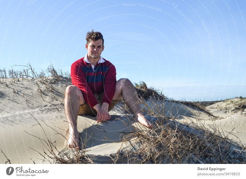 Typ im rot-blauen Rugby-Hemd auf Sanddünen sitzend Strand Stranddüne Ferien & Urlaub & Reisen Küste Düne Meer Erholung
