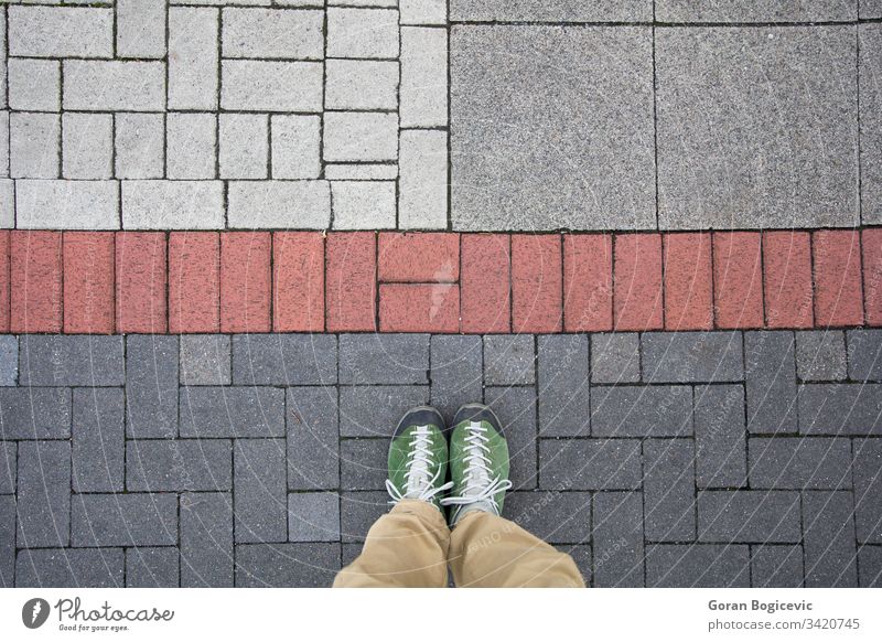 Draufsicht auf einen Mann, der auf dem farbigen geometrischen Pflaster steht Straße Straßenbelag im Freien Fuß reisen Stock Stein Boden Schuh Person Bürgersteig