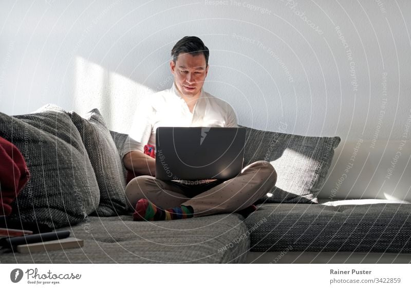 Mann arbeitet von zu Hause aus mit einem Laptop im Wohnzimmer Erwachsener lässig Computer Textfreiraum Unternehmer Freiberufler heimwärts Heimarbeitsplatz