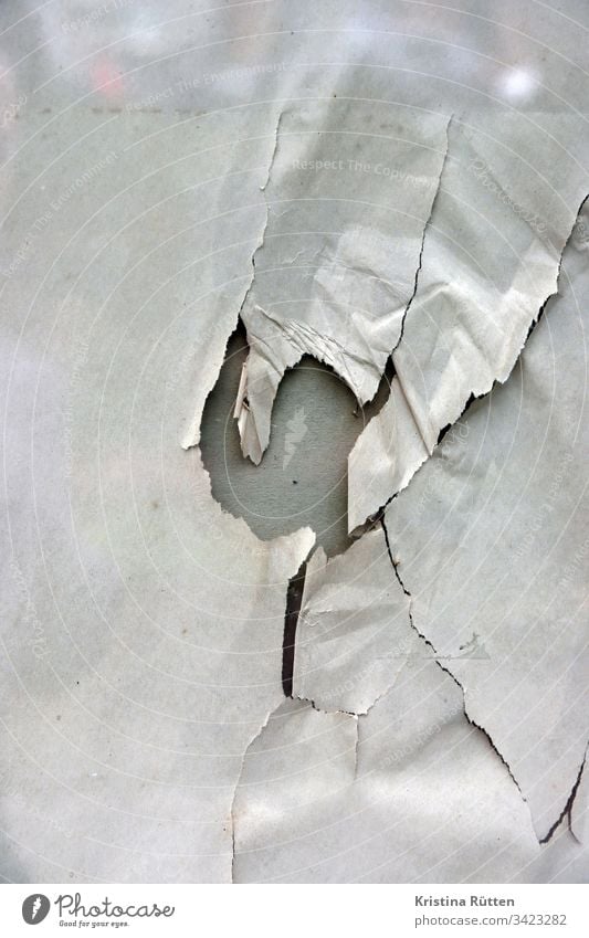papier mit loch hinter glasscheibe packpapier gerissen kaputt fenster schaufenster spiegelung struktur textur hintergrund material oberfläche zerstört abstrakt