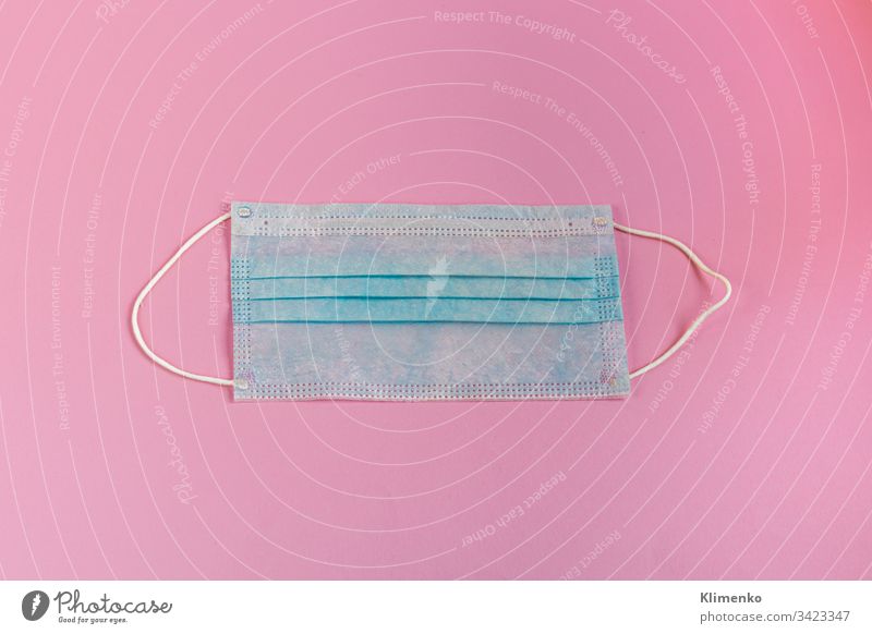 Eine Hygieneschutzmaske hilft, das Eindringen des Corona-Virus oder von Covid-19 und anderen Krankheiten zu verhindern. Blau auf rosa. Ansicht von oben.