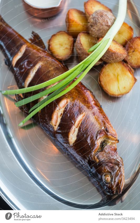 Gegrillter Fisch und Kartoffeln mit Frühlingszwiebeln und Sauce Grillrost Restaurant Teller Saucen Sahne Lebensmittel Mahlzeit lecker Meeresfrüchte