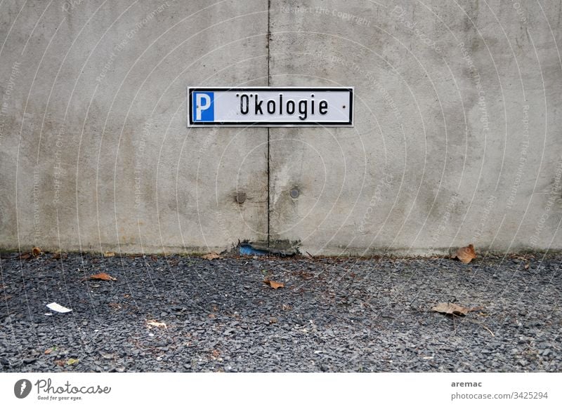 Ökologie Schild auf Betonwand mit Schotter Parkplatz Mauer Widerspruch Humor Reservierung