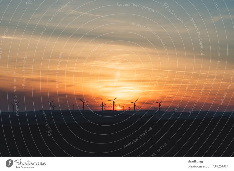 Sonnenuntergang über einem Feld mit Windrädern Wolken Himmel Windrad Energieerzeugung Infrastruktur Windkraftanlage Farbfoto Energiewirtschaft