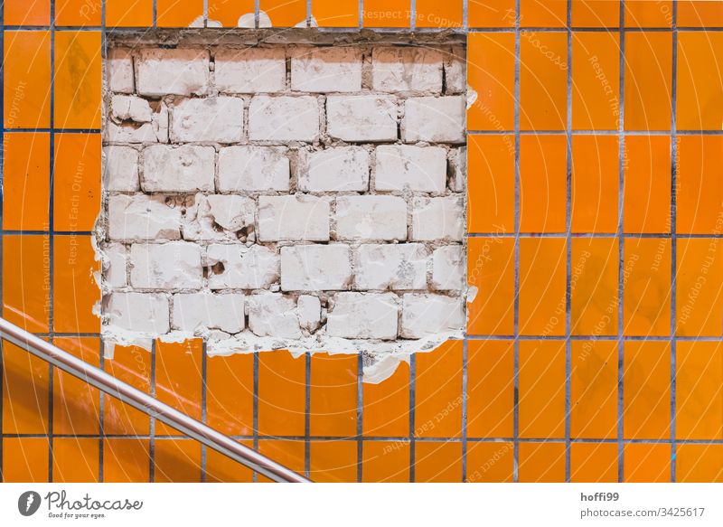 Abgeplatzt Fliesen öffnen den Blick aufs Mauerwerk Reparatur Mauersteine Kalksandstein Schaden Ausbesserungswerk Mauern kaputt Lücke beschädigung orange weiß