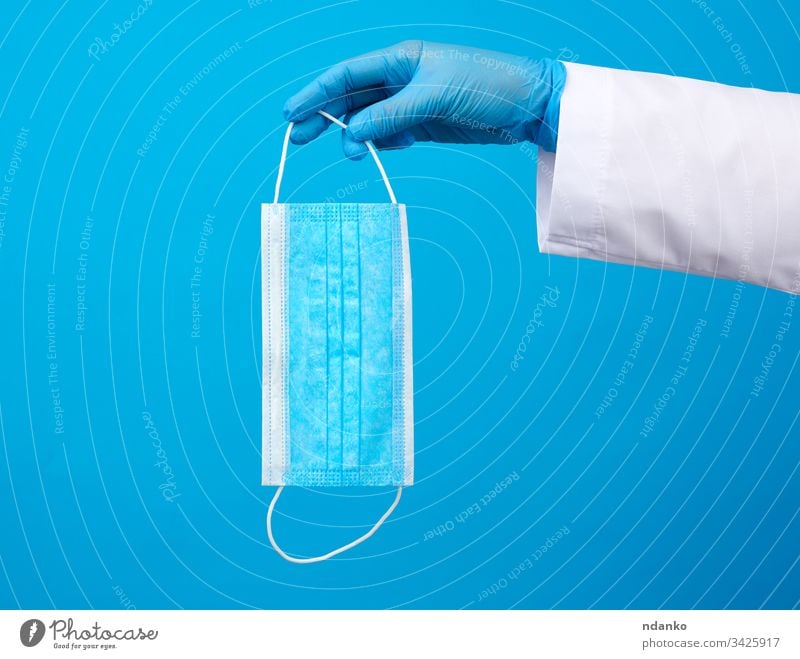 Arzt in blauen sterilen Latexhandschuhen hält eine blaue Einwegmaske aus Vliesstoff Mundschutz Sanitäter medizinisch Medizin Krankenpfleger Beruf Frau