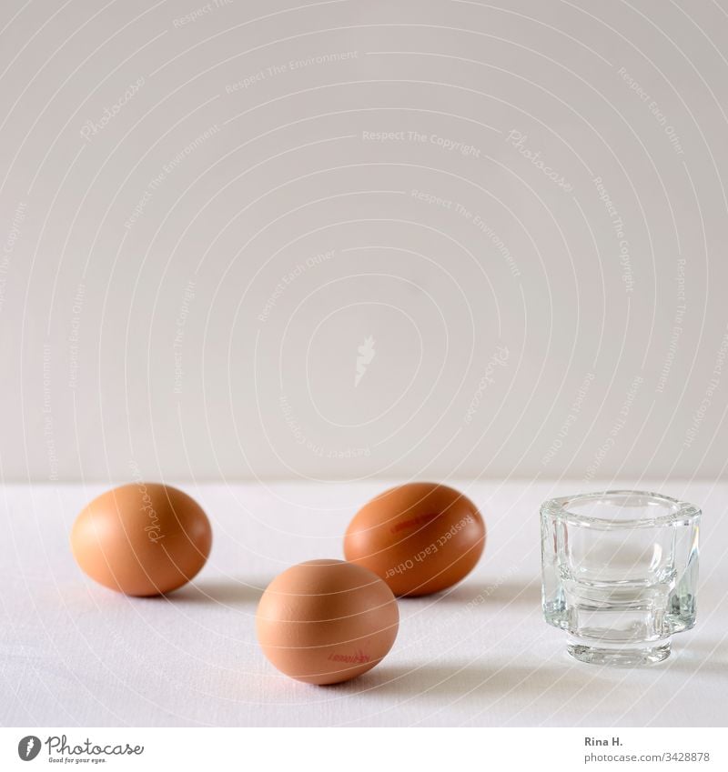 Drei braune Eier und ein Eierbecher Ostern minimalismus Osterei Frühstück Farbfoto gekochte Eier Lebensmittel Innenaufnahme Menschenleer