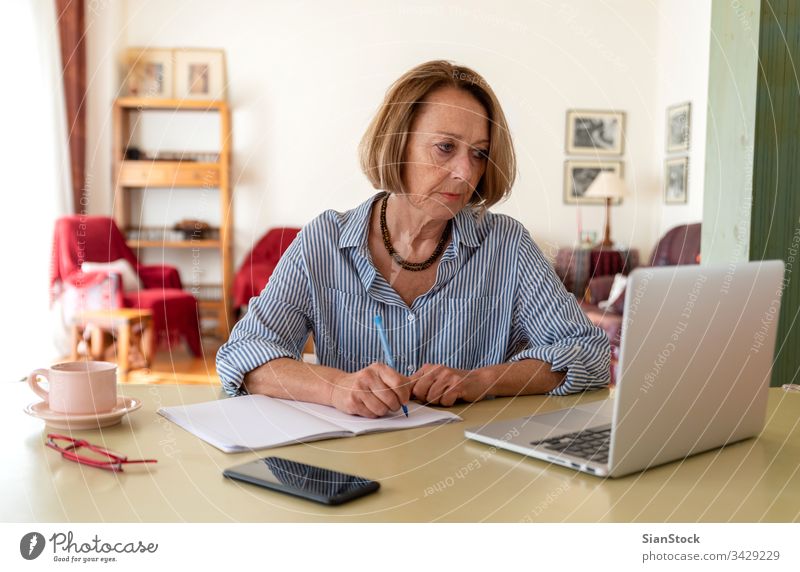 Senioren mittleren Alters, die zu Hause am Computer arbeiten Frau Laptop reif Menschen eine Person Lifestyle Schreibtisch benutzend trinken Brille attraktiv