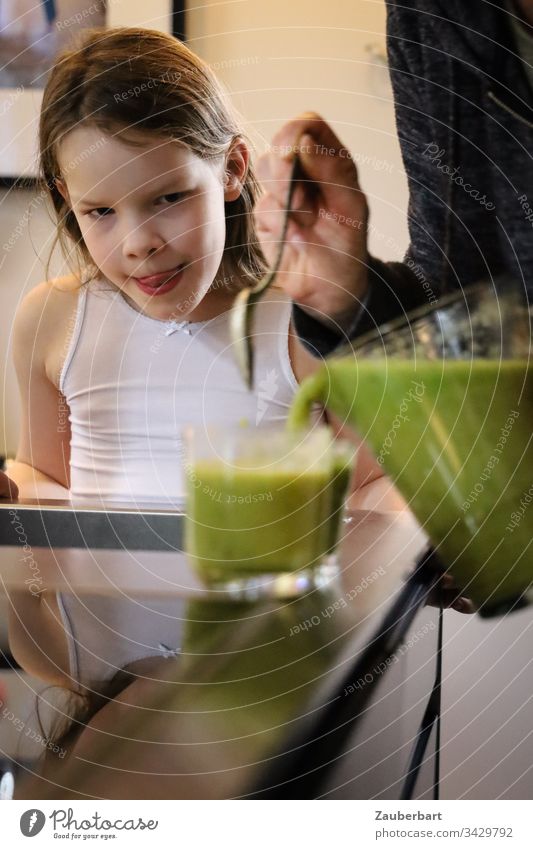 Kleines Mädchen schaut zu, wie grüner Smoothie in ein Glas gegossen wird, und freut sich darauf Kind Kindheit lecker gesund Getränk Karaffe selbstgemacht Hand