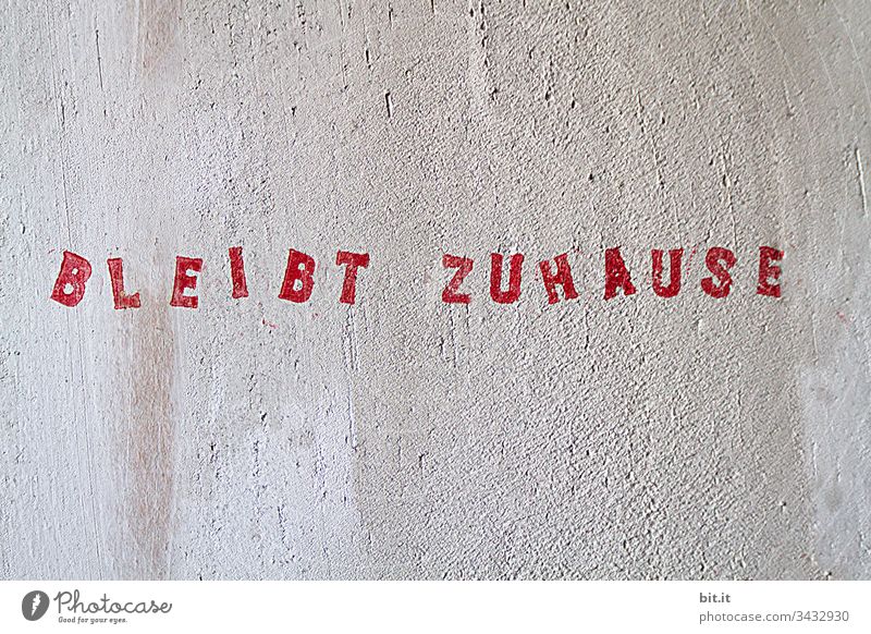 Bleibt Zuhause, roter Schriftzug mit Stempel auf weisse Wand gestempelt. COVID Quarantäne Prävention Coronavirus Ansteckend infektiös Hinweisschild Schützen