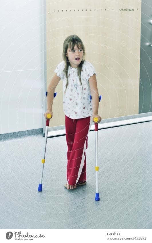 kleines mädchen auf krücken im krankenhaus Kind Mädchen laufen Krücken Krankenhaus Verletzung Unfall Behandlung Barfuß farbig Schockraum Schrift Krankenhausflur