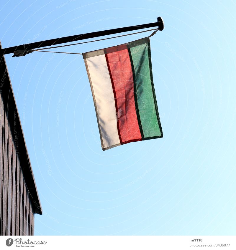 Fahne an Fahnenstange mit den Farben von Helgoland hängt vor blauem Himmel vom Gebäude herunter Flagge Fahnenmast blauer Himmel Hintergrund neutral menschenleer
