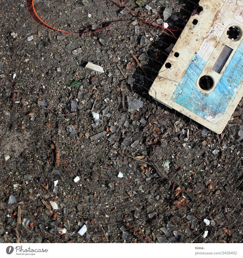 süße kleine verdreckte Audiokassette kunststoff schatten sonnenlicht abdruck dreckig schmutzig detail linien oberfläche trashig kaputt sandig teerboden cassette