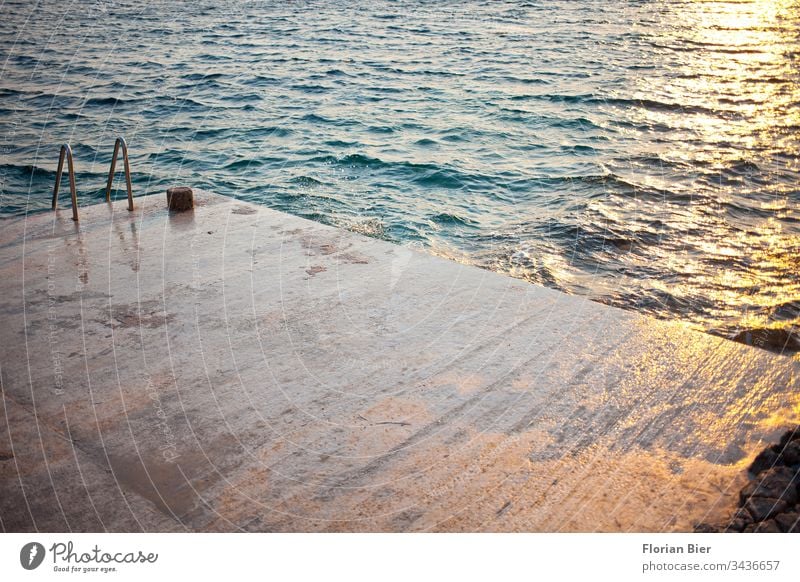 Nasse Betonierte Liegefläche mit Schwimmleiter ins Meer bei Sonnenuntergang Betonboden Leiter liegefläche Wellen Spiegelung Wasser Reflexion & Spiegelung Abend