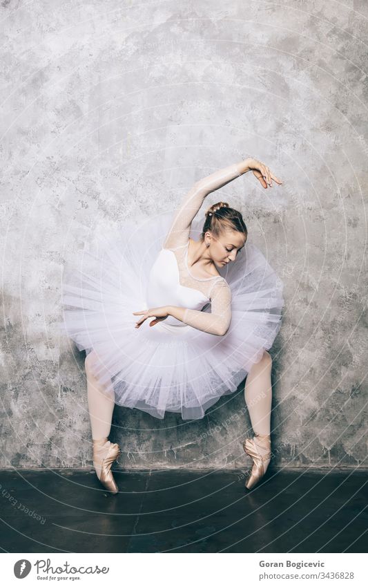 Elegante Ballerina in weißem Kleid tanzt gegen eine rustikale Wand Aktion Erwachsener attraktiv Hintergrund Gleichgewicht Balletttänzer Körper Choreographie